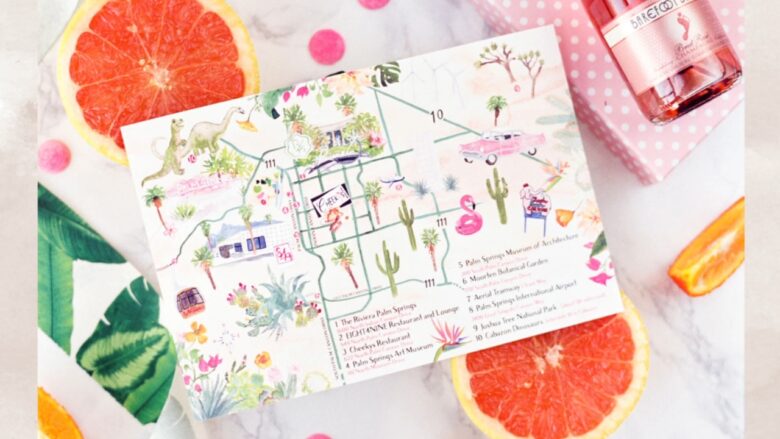 Wedding guest city map with citrus slices and a pink drink on a marble table