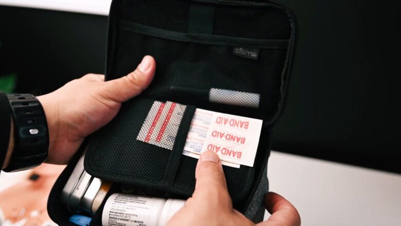 Hands hold a small emergency kit with bandages, medicine, and travel supplies