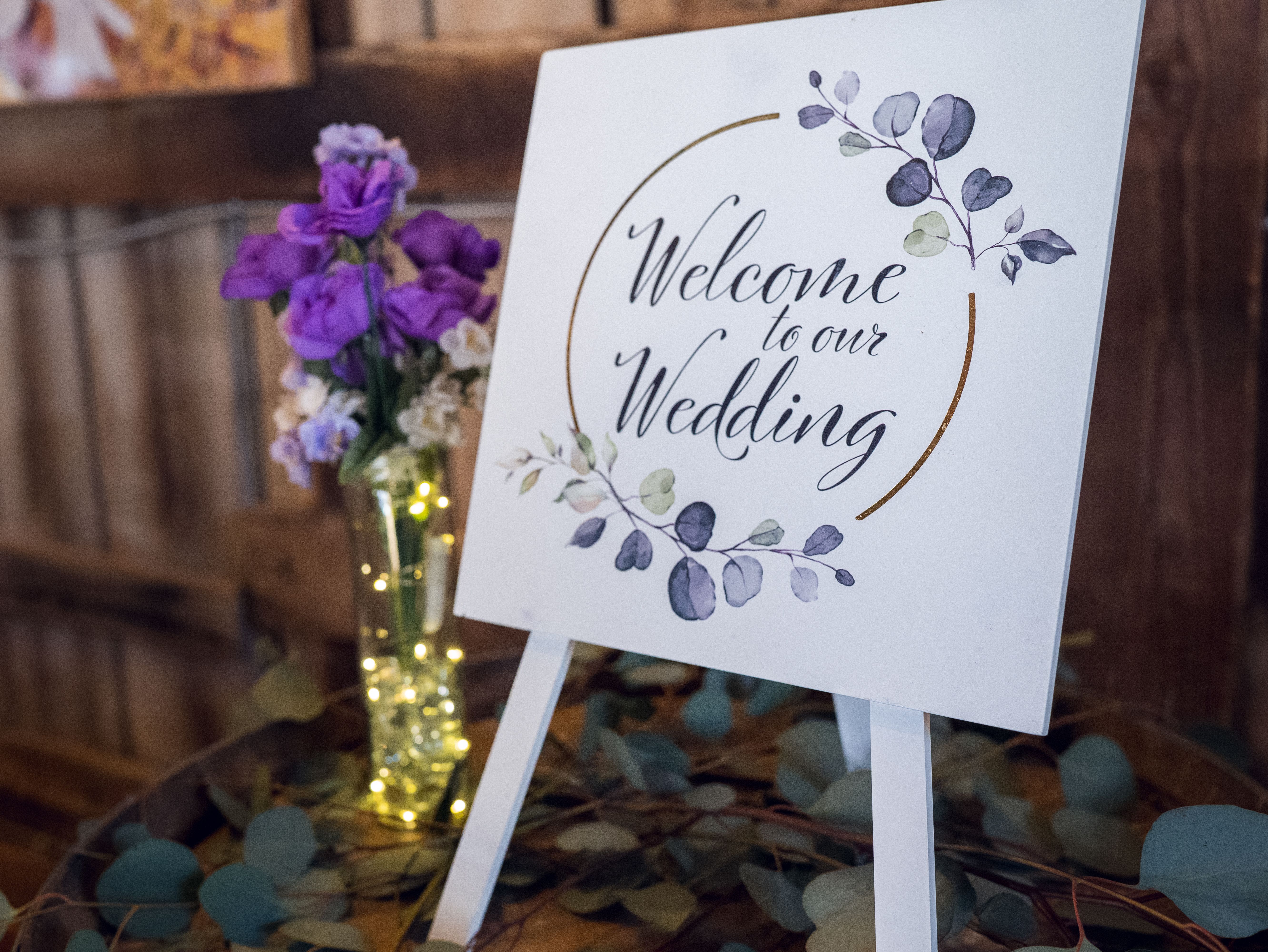 Wedding welcome sign decorated with purple flowers and elegant lettering for a personal DIY entrance display.
